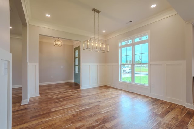 unfurnished dining area with crown molding, wood-type flooring, and a chandelier