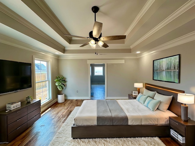 bedroom featuring crown molding, a tray ceiling, dark hardwood / wood-style floors, and ceiling fan