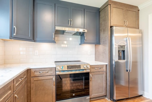 kitchen featuring stainless steel appliances, light stone countertops, light hardwood / wood-style floors, and decorative backsplash