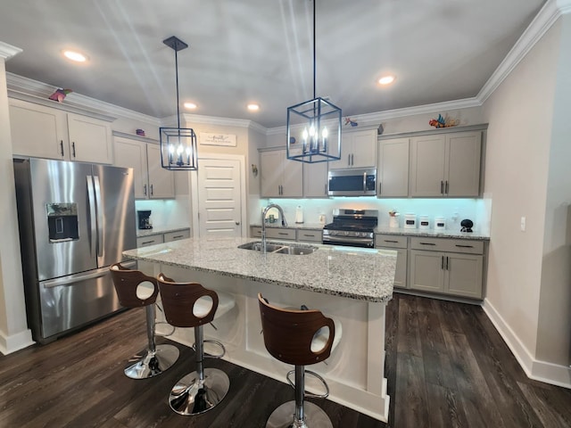 kitchen featuring sink, dark hardwood / wood-style floors, appliances with stainless steel finishes, decorative light fixtures, and light stone counters