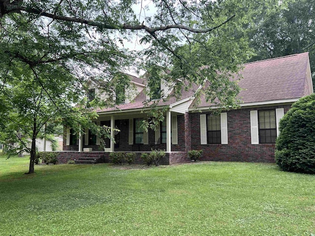 view of front of house featuring covered porch, a front lawn, brick siding, and roof with shingles