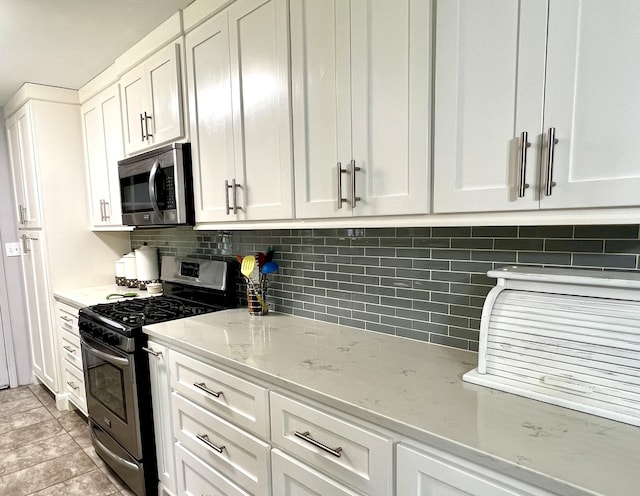 kitchen with appliances with stainless steel finishes, white cabinets, decorative backsplash, and light stone countertops