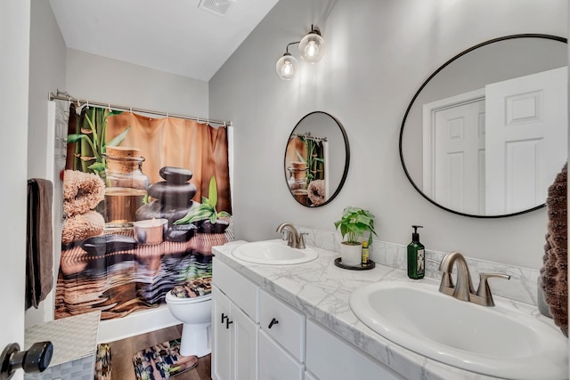 bathroom featuring visible vents, toilet, wood finished floors, and a sink