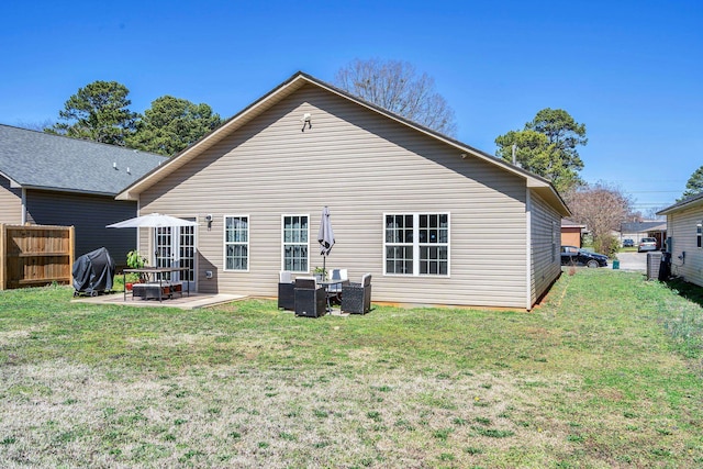 back of property featuring fence, a lawn, and a patio area