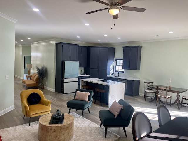 kitchen with refrigerator, light hardwood / wood-style floors, a kitchen island, ceiling fan, and ornamental molding