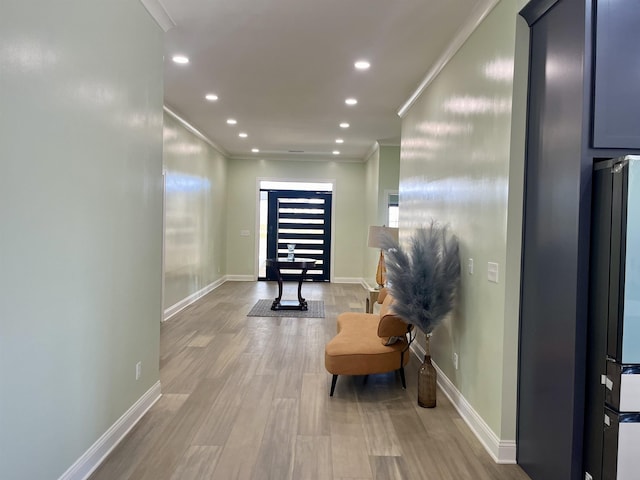 hallway with light hardwood / wood-style floors and crown molding