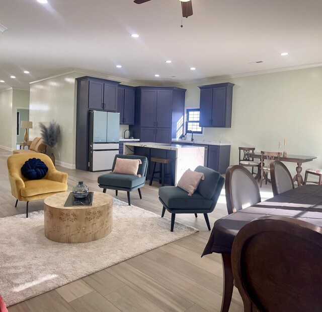 living room with light hardwood / wood-style floors, ceiling fan, ornamental molding, and sink