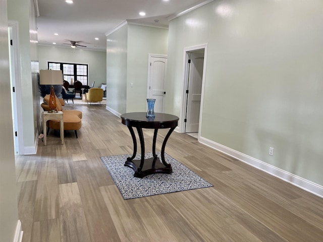 hallway with ornamental molding and light hardwood / wood-style floors