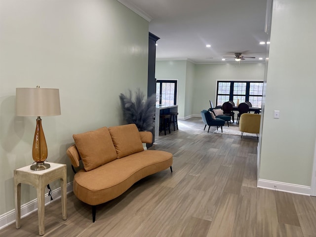 sitting room featuring ceiling fan, crown molding, and wood-type flooring