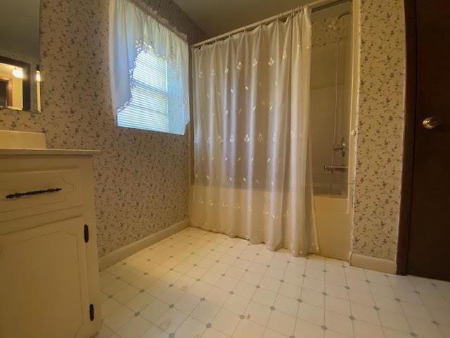 full bath with vanity, baseboards, wallpapered walls, tile patterned floors, and shower / tub combo with curtain