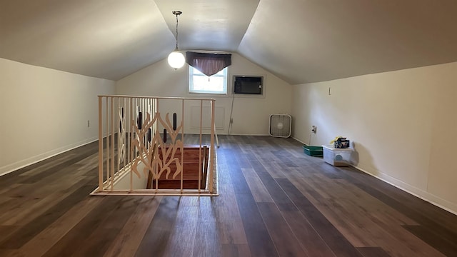 additional living space featuring a wall mounted air conditioner, vaulted ceiling, and dark wood-type flooring