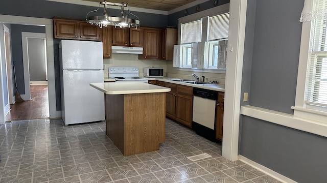 kitchen with white appliances, sink, pendant lighting, a chandelier, and a kitchen island