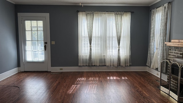 entryway featuring crown molding, dark wood-type flooring, a textured ceiling, and a brick fireplace