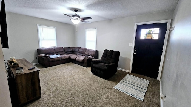 carpeted living room featuring ceiling fan and a textured ceiling