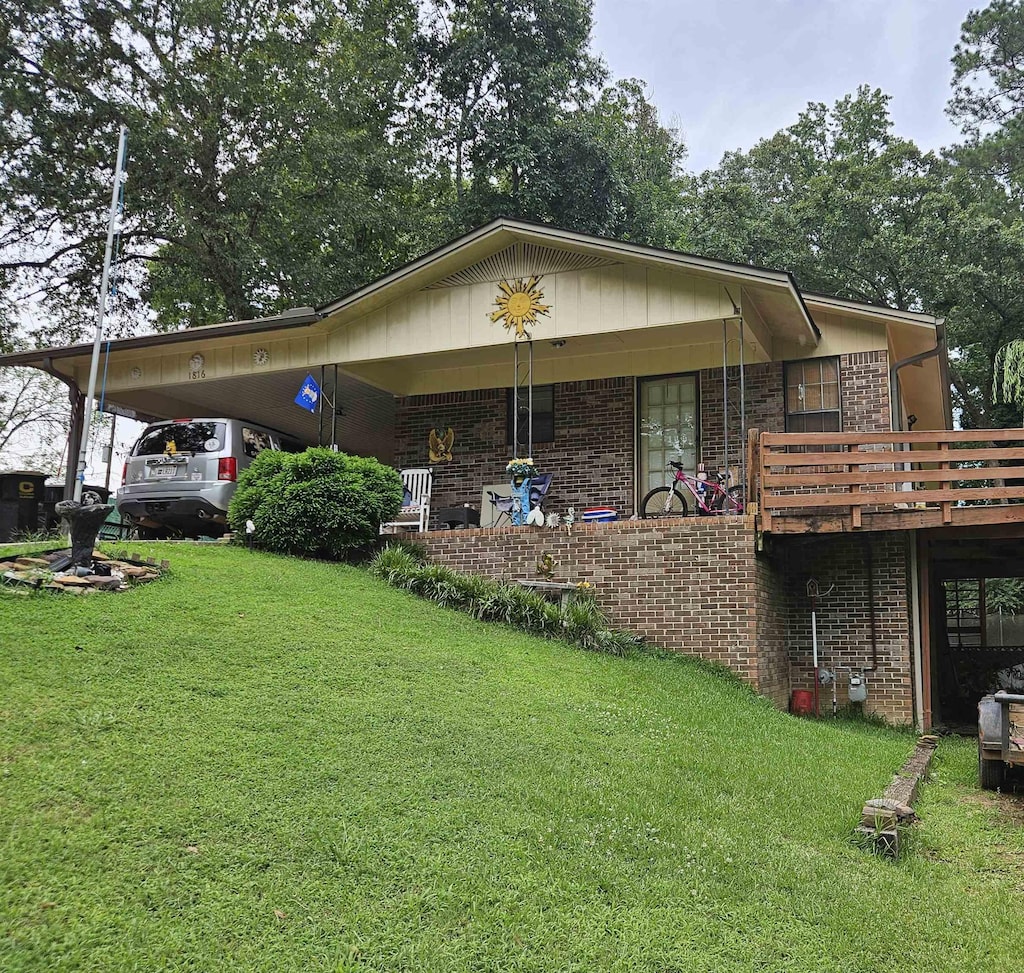  - rear view of property with brick siding, a lawn, and an attached carport