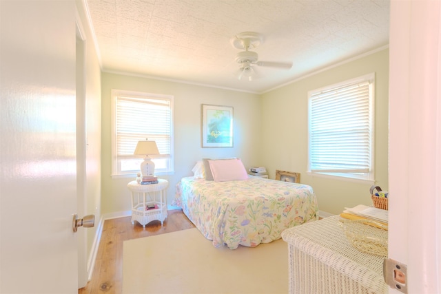bedroom with multiple windows, crown molding, light wood-style floors, and baseboards