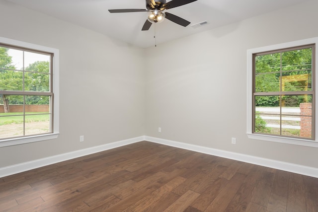 spare room featuring a healthy amount of sunlight, ceiling fan, and dark wood-type flooring