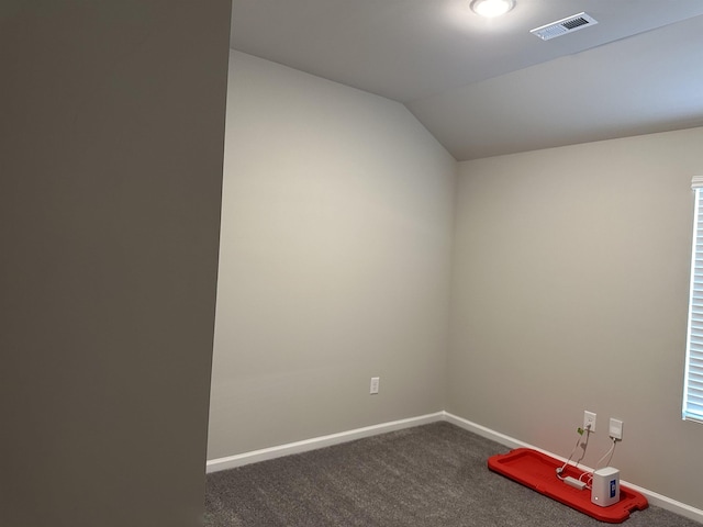 unfurnished room featuring dark carpet and vaulted ceiling