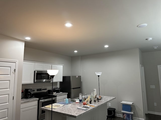 kitchen with white cabinets, light stone counters, a kitchen island with sink, and appliances with stainless steel finishes