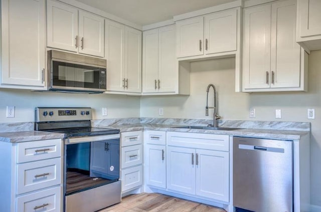 kitchen featuring white cabinets, light wood-type flooring, sink, and appliances with stainless steel finishes