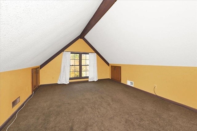 additional living space featuring dark carpet, lofted ceiling, and a textured ceiling