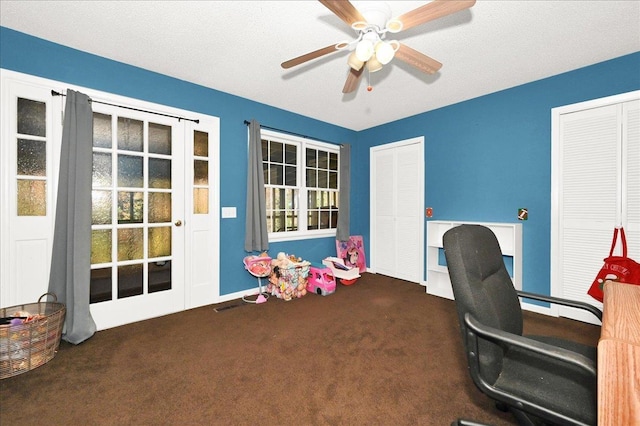 carpeted office space with a textured ceiling and ceiling fan