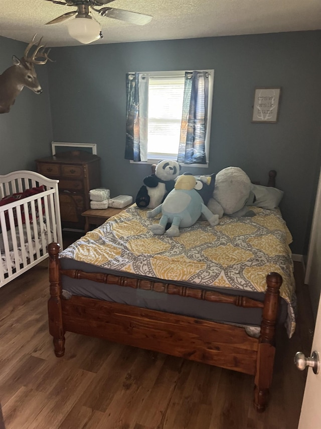 bedroom featuring ceiling fan, dark hardwood / wood-style flooring, and a textured ceiling