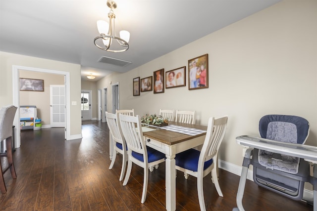 dining space with dark hardwood / wood-style flooring and an inviting chandelier