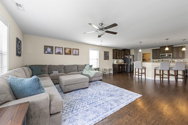 living room with ceiling fan and dark wood-type flooring