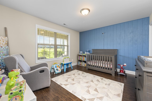 bedroom with dark hardwood / wood-style flooring and a crib