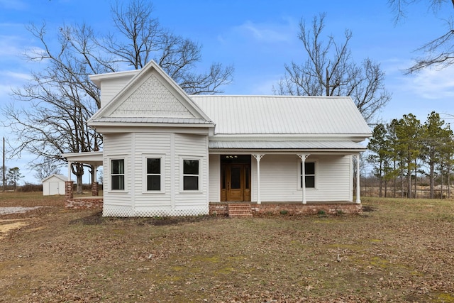 view of front of property featuring a porch and a storage shed