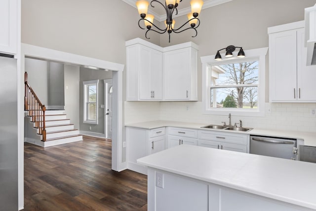 kitchen with hanging light fixtures, sink, stainless steel dishwasher, and white cabinets