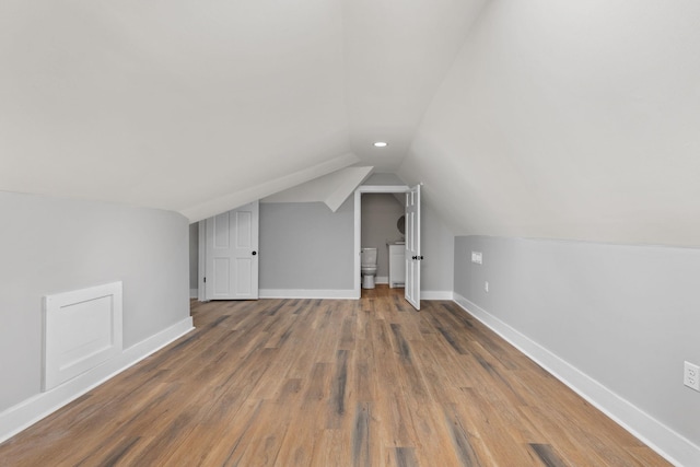 additional living space with hardwood / wood-style flooring and vaulted ceiling