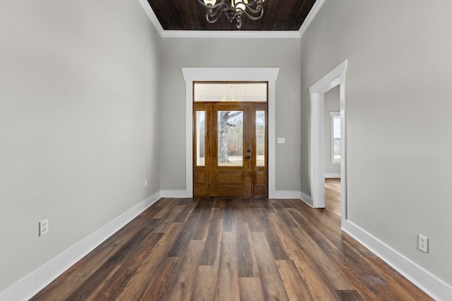 foyer entrance featuring dark hardwood / wood-style flooring, ornamental molding, and an inviting chandelier