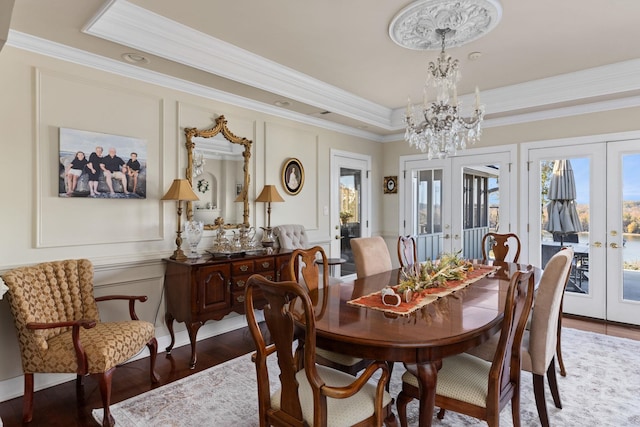 dining room with french doors, an inviting chandelier, wood-type flooring, a tray ceiling, and ornamental molding