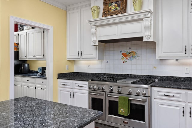 kitchen with white cabinets, backsplash, stainless steel range, and dark stone counters