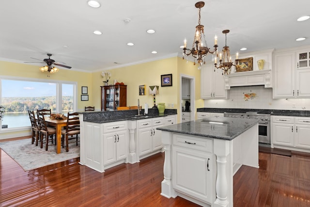 kitchen featuring ceiling fan with notable chandelier, dark wood-type flooring, white cabinets, a kitchen island, and hanging light fixtures