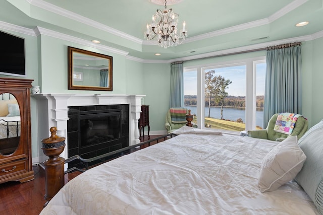 bedroom featuring a raised ceiling, a tiled fireplace, hardwood / wood-style floors, and a water view