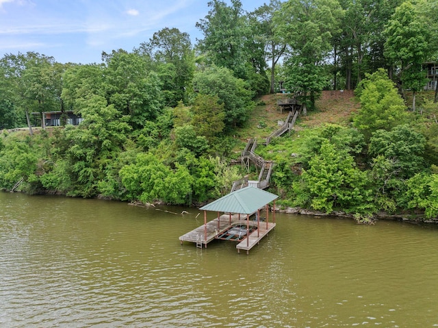 dock featuring boat lift, a water view, and view of wooded area