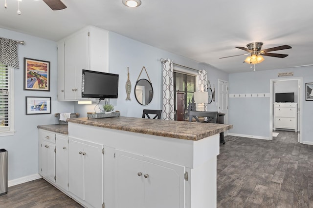 kitchen featuring ceiling fan, dark wood-style flooring, a peninsula, white cabinetry, and baseboards