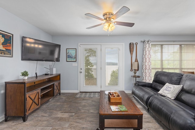 living area with a ceiling fan and baseboards