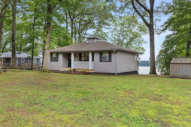 view of front of property with covered porch, a front yard, and an outdoor structure