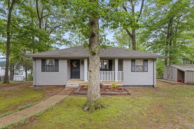 view of front of home featuring a storage shed, a porch, an outdoor structure, and a front yard