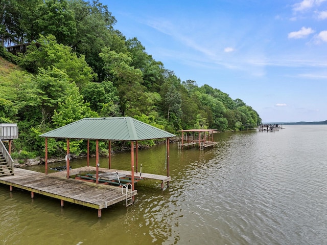 dock area with a water view, stairway, and a view of trees