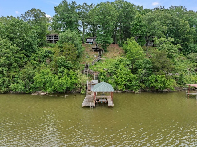 dock featuring boat lift, stairs, and view of scattered trees