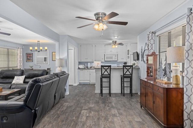 living room featuring ceiling fan, dark wood-style flooring, and a chandelier