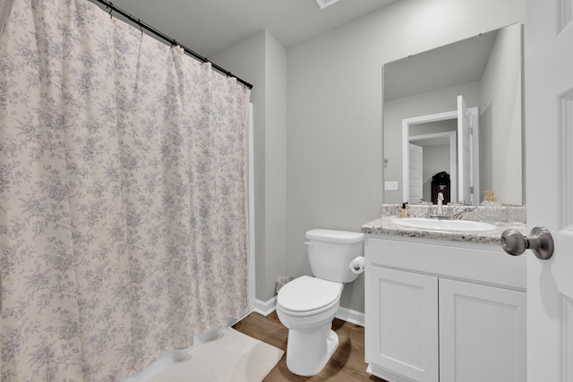  - bathroom with toilet, wood finished floors, vanity, a shower with curtain, and baseboards