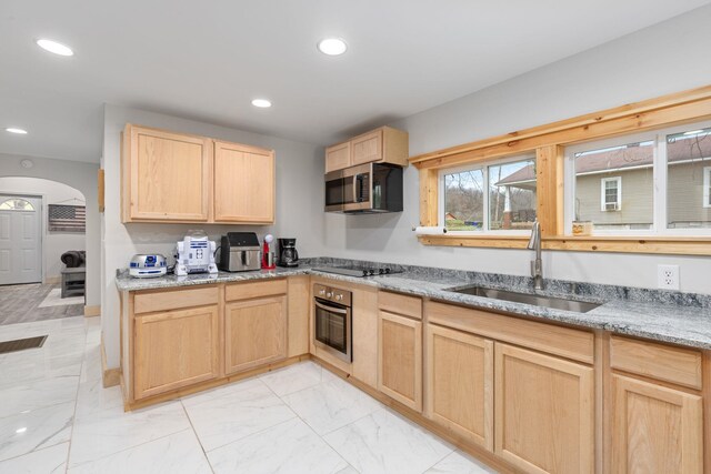 kitchen with light brown cabinetry, sink, light stone counters, and appliances with stainless steel finishes