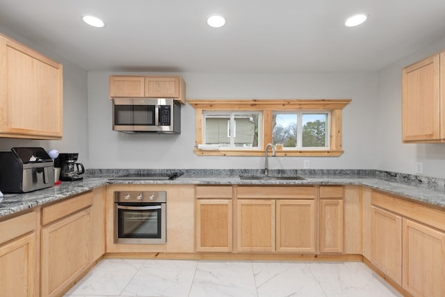 kitchen with light brown cabinetry, sink, light stone counters, and appliances with stainless steel finishes