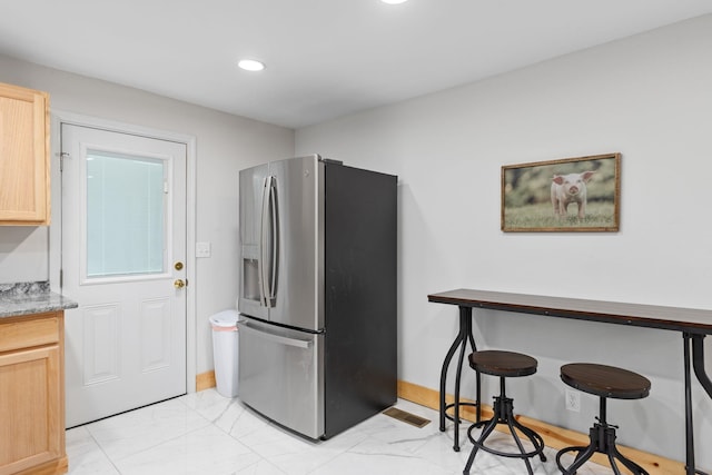 kitchen featuring stainless steel refrigerator with ice dispenser and light brown cabinetry